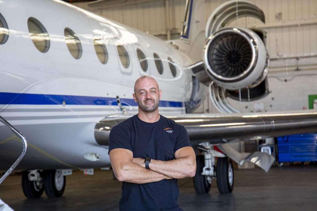 Matt Stull Aviation Maintenance Technician at Constant Aviation poses in front of Gulfstream business jet