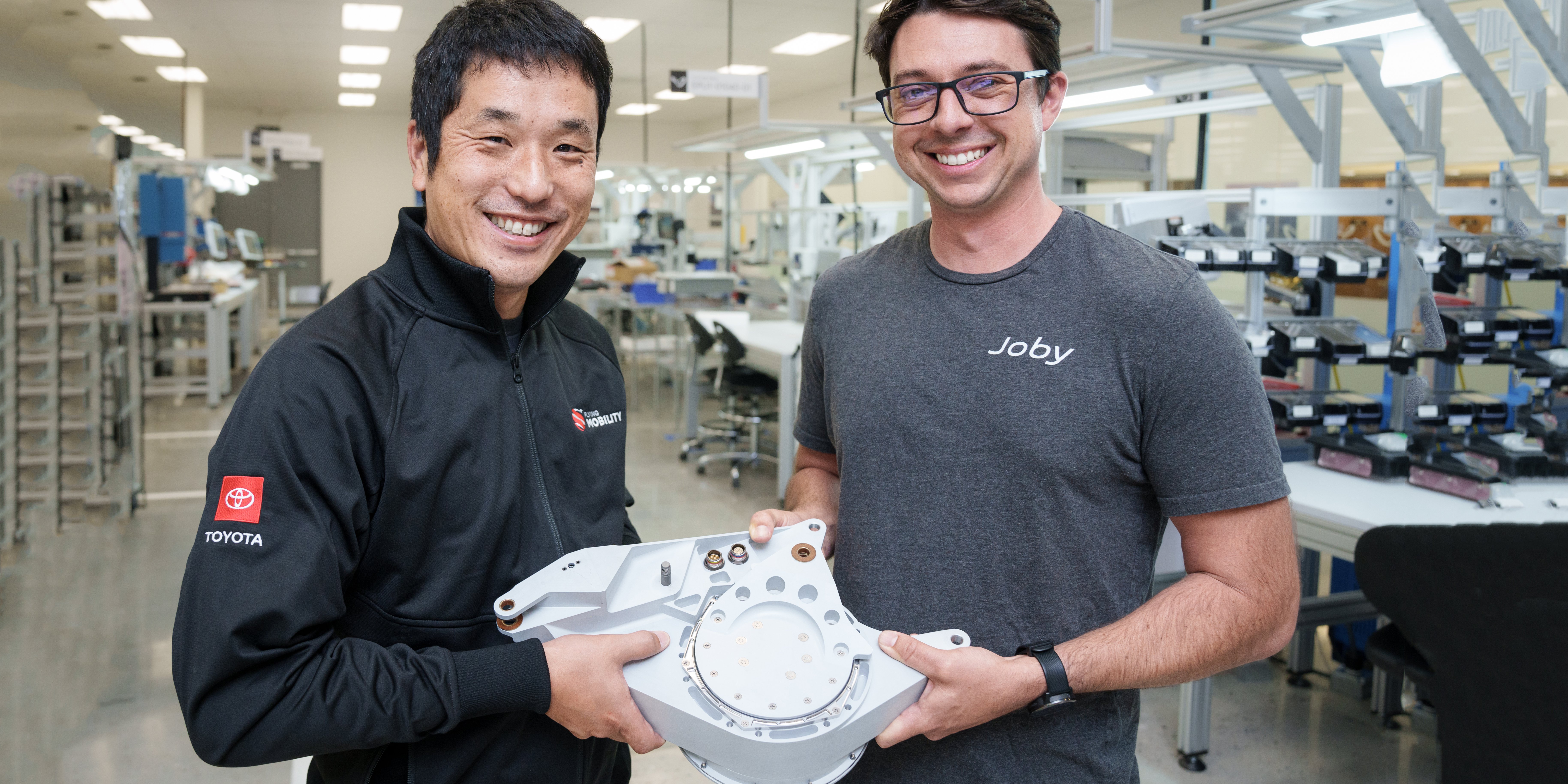 Two Joby engineers are pictured holding a tilt actuator at Joby’s San Carlos production facility.