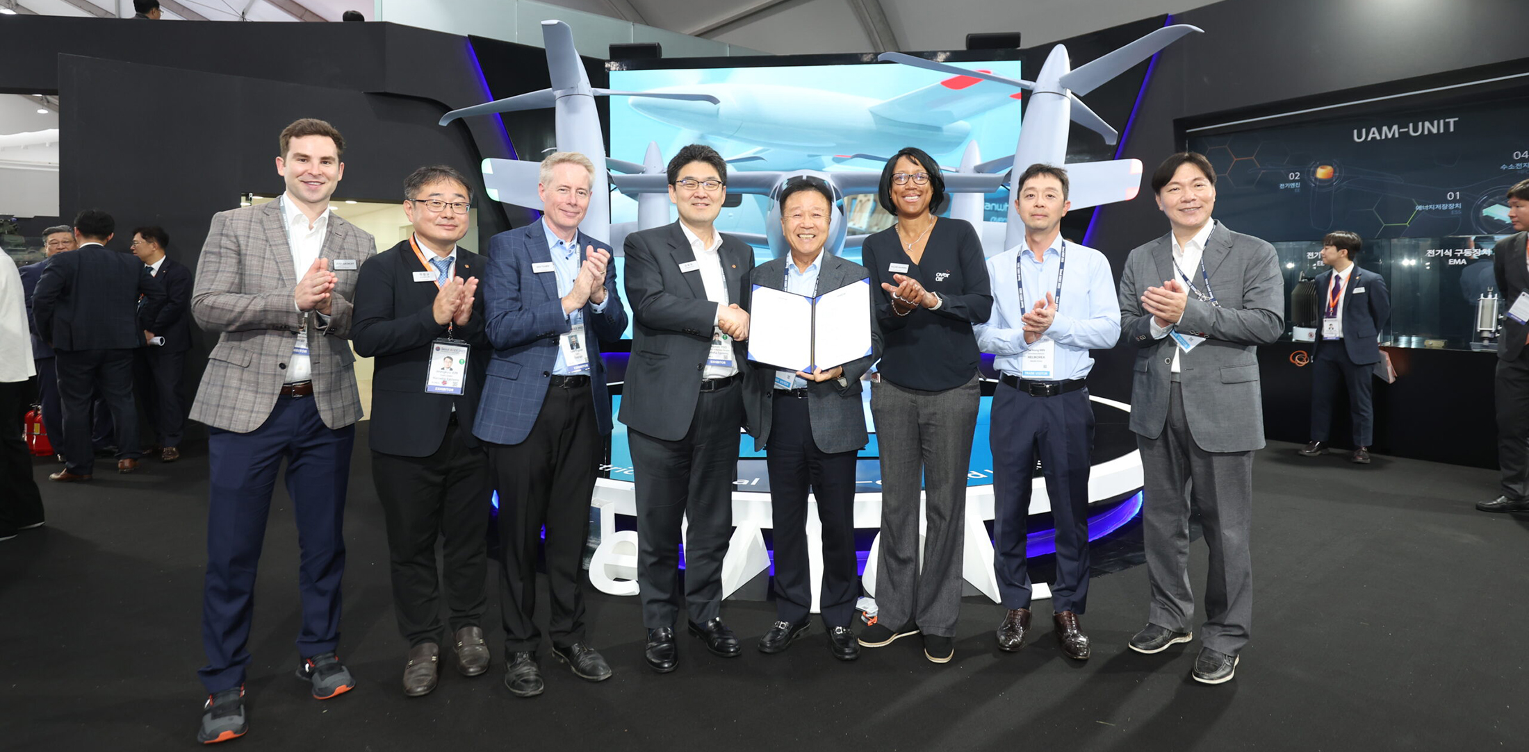 HeliKorea and Overair representatives pose with the signed letter of intent in front of a mockup of the Butterfly eVTOL aircraft