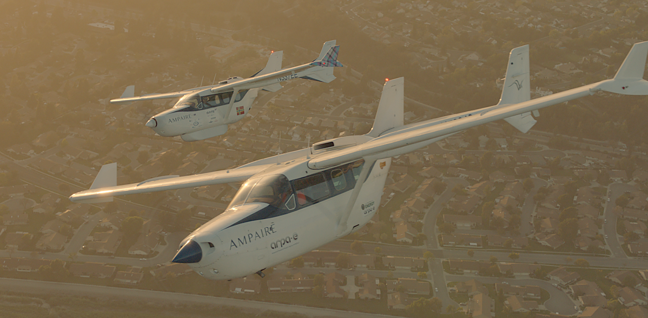 Two Ampaire hybrid-electric technology demonstrator aircraft fly in formation over California. The ARPA-E Bird, depicted in the foreground, is used to test new technology on behalf of ARPA-E.