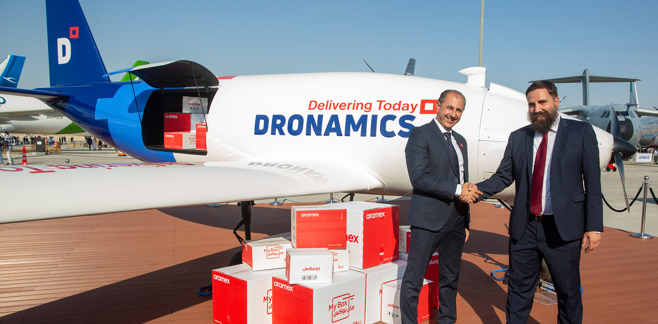 Aramex Chief Operating Officer Alaa Saoudi (left) and Dronamics co-founder and CEO Svilen Rangelov shake hands in front of a Dronamics Black Swan cargo drone after signing a letter of intent at the Dubai Airshow in November 2023