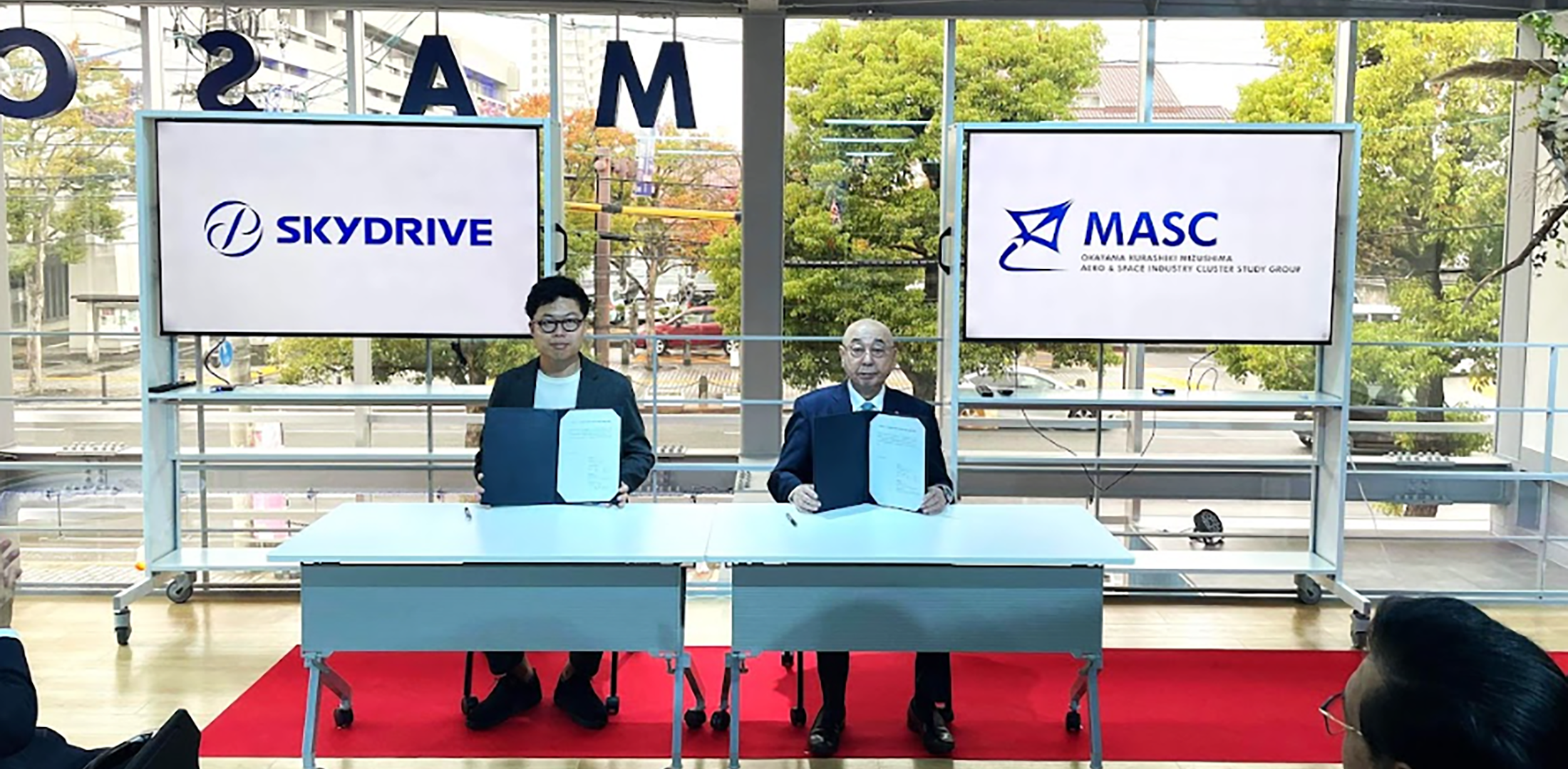 SkyDrive CEO Tomohiro Fukuzawa (left) and MASC president Minehito Inoue signed a memorandum of understanding during a ceremony held at an eVTOL exhibition hall in Kurashiki-city on Nov. 10, 2023.