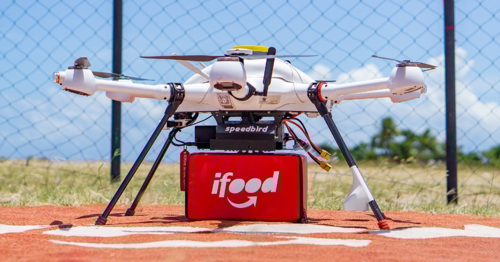 Speedbird Aero drone on a landing pad carrying an iFood delivery container.