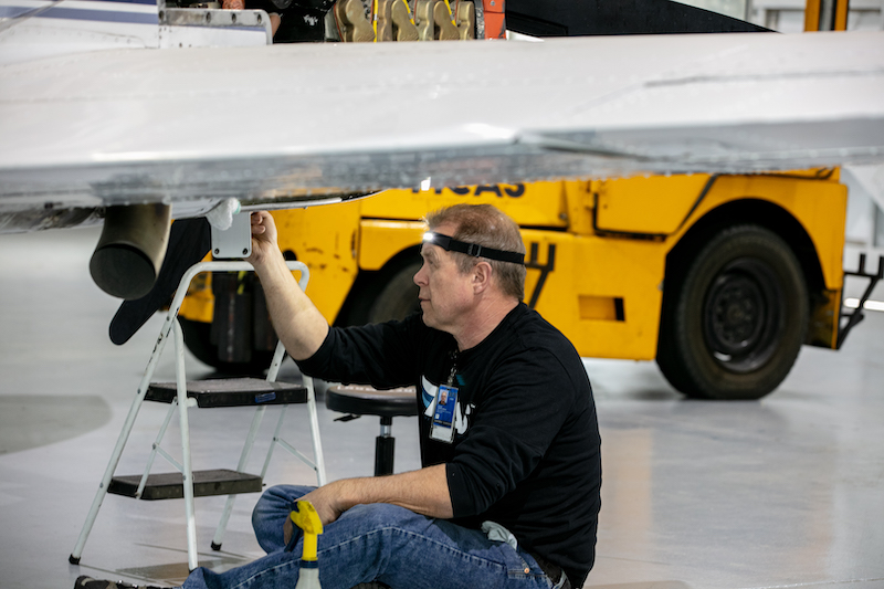 MCAS technician at work underneath aircraft wing
